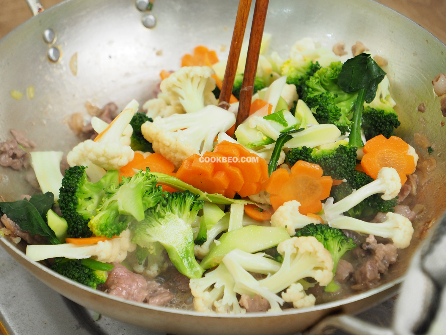 Thịt chín thì cho súp lơ và cà rốt vào xào